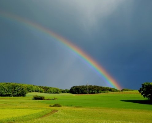 A picture of a pasture in upstate new york after a thunderstorm with a rainbow in the sky, this image is used to teach about the weather in Spanish language instruction NYC